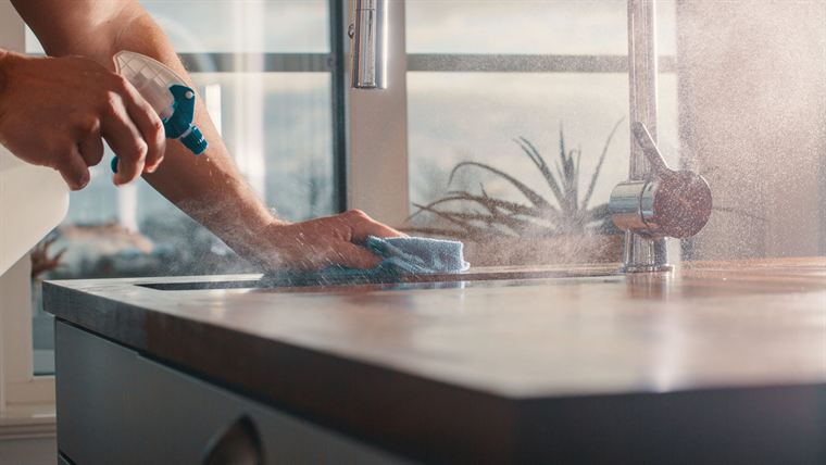 Wiping down a kitchen counter beside the sink