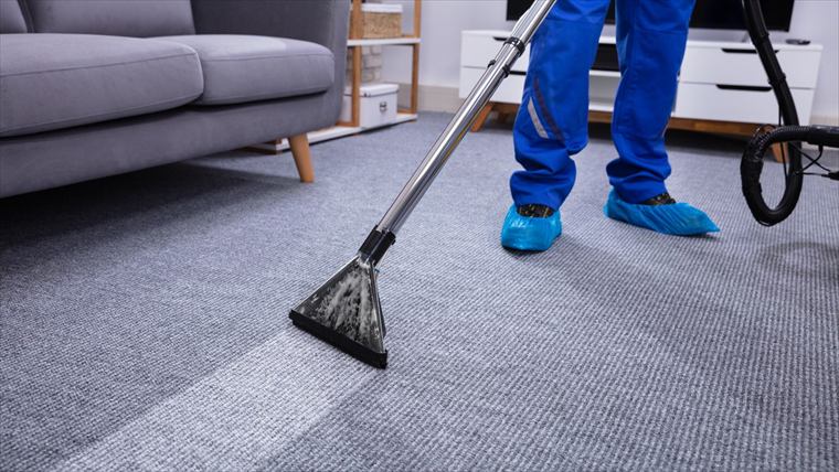 Vacuuming the floor next to a sofa